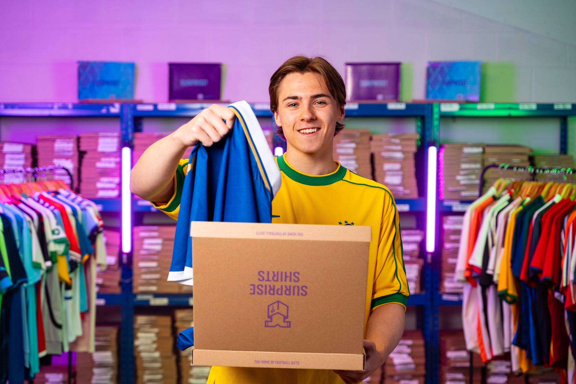 Louis pulls a blue shirt out of an open Surprise Shirts box